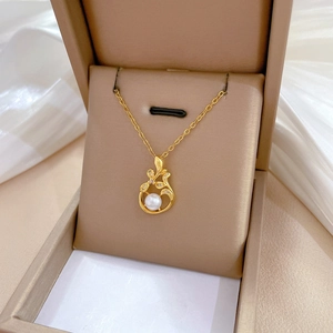 Detail view of a gold leaf necklace with pearl and sparkling zircons in a jewelry gift box