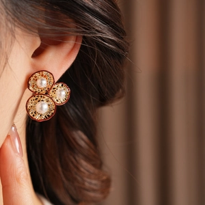 Detailaufnahme von Vintage-Blumenohrringen mit Perlen am Ohr eines Models