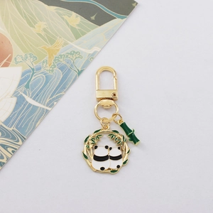Close-up of golden panda keychain with green bamboo ring and panda couple details