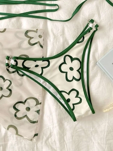 Détail du bas de bikini avec motif floral vert et anneaux métalliques sur les côtés