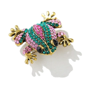 Détail d'une broche grenouille vintage avec strass verts sur une base en métal doré