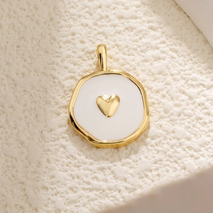 Macro view of white enamel heart pendant with golden relief in irregular round frame