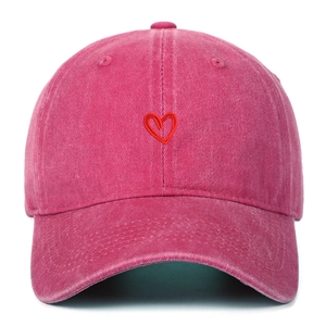 Dettaglio del ricamo a cuore sulla tela di cotone lavato di questo berretto rosa