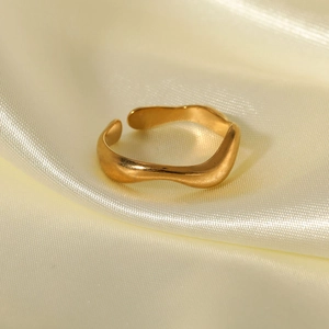 Minimalist gold-plated stainless steel wavy open ring displayed on silk fabric