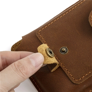 Macro shot of crazy horse leather phone pouch showing brass snap button and stitching detail