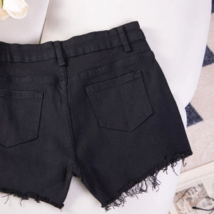 Dettaglio delle tasche posteriori e dell'orlo sfrangiato dei pantaloncini di jeans neri