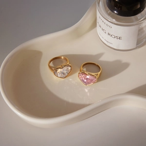 Detailed view of heart-shaped crystal rings in pink and white on a ceramic tray
