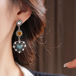 Detailed view of vintage silver drop earrings with blue heart rhinestone and white pearls