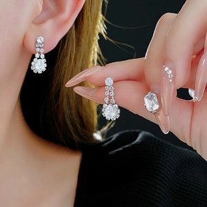 Macro shot of silver drop earrings with shimmering cubic zirconia on model's ear