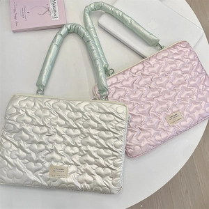 Close-up of heart-quilted laptop sleeves in silver and pink with soft padded handles