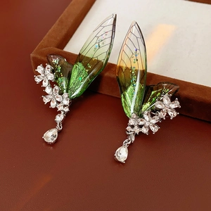 Dettaglio orecchino argento con ala verde sfumata, fiore di strass e goccia pendente