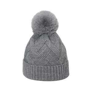 Bonnet en tricot d'hiver gris classique avec pompon en fausse fourrure sur fond blanc