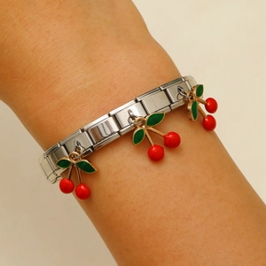 Detail eines italienischen Charm-Armbands mit drei roten Kirsch-Anhängern am Handgelenk