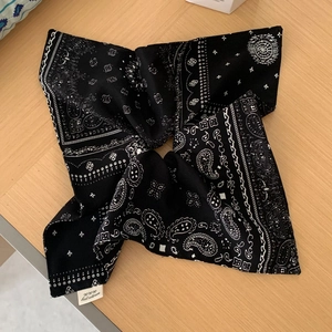 Vue à plat d'un foulard en tissu à imprimé cachemire noir et blanc sur bois