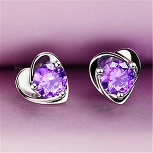 Close-up of heart-shaped silver earrings with sparkling purple zircon on purple velvet