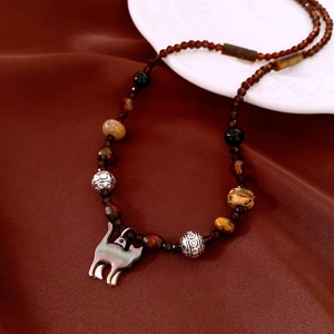 Detail of vintage beaded necklace with iridescent cat pendant on brown silk fabric