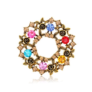 Detail of vintage gold wreath brooch with colorful rhinestones and floral metal leaves