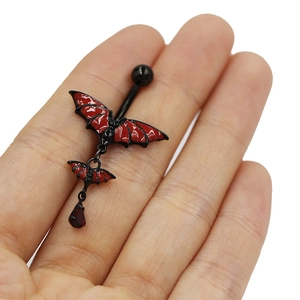 Macro shot of a red and black Gothic bat belly button ring with a red teardrop pendant