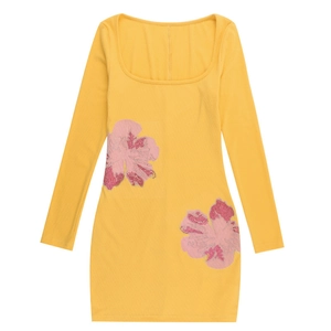 Dettaglio di maglia a coste gialla con fiori di paillettes rosa e scollo a U profondo