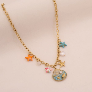 Dettaglio ravvicinato di una collana dorata con ciondoli a forma di stella marina e conchiglie