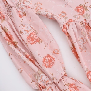 Détail du tissu en mousseline à imprimé rose avec micro-plis et bords à volants