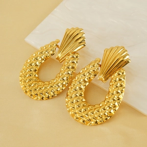 Golden vintage U-shaped geometric earrings with textured pineapple pattern on white marble