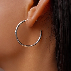 Close-up of minimalist silver hoop earrings on a model showing polished metal finish