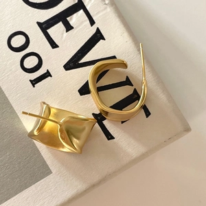 Minimalist asymmetrical 925 sterling silver earrings with matte gold finish on textured paper