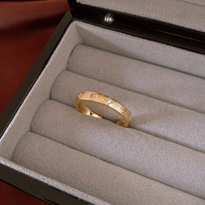 Close-up of golden star engraved ring with sparkling zircon in grey velvet jewelry box