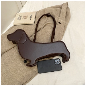 Detailed view of dark brown dachshund dog shaped tote bag on a beige blazer with phone for scale