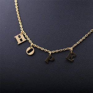 Gros plan du collier en acier inoxydable doré avec pendentifs lettres HOPE sur cuir