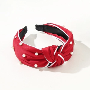 Close-up of red knotted Christmas headband with white pearls and luxury fabric detail