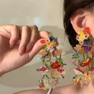 Detailed close-up of colorful resin flower tassel earrings worn on model for display