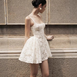 Mini robe élégante en dentelle blanche à fines bretelles et motif floral sur mannequin