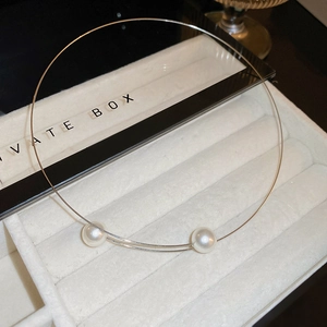 Détail d'un collier ras du cou perle minimaliste sur un plateau à bijoux en velours beige