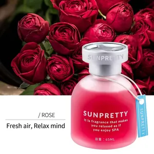 Close-up of 65ml frosted pink glass car fragrance bottle surrounded by fresh red roses