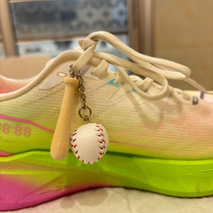 Close-up of baseball bat keychain pendant attached to a gradient mesh sports sneaker