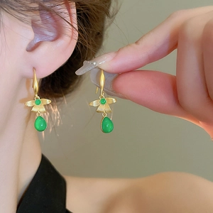 Vintage green resin teardrop earrings with gold flower detail on a model