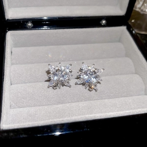 Close-up of snowflake stud earrings with 18k gold plating and sparkling zircon stones