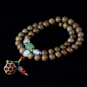 Macro detail of sandalwood beads with carved lotus seed pod and colorful accents