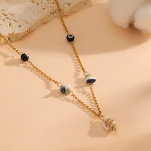 Bohemian gold chain necklace with evil eye beads and natural shell pendant on a stone base