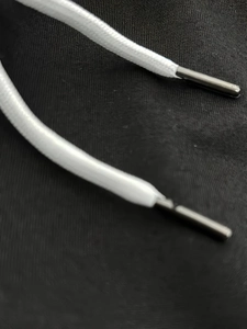Détail du cordon de serrage blanc avec embouts métalliques sur tissu en maille noir