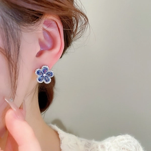 Close-up of blue zircon flower earrings worn by a model with delicate petal details