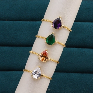 Détail de bagues chaînettes or 18k avec pierres précieuses colorées en forme de poire