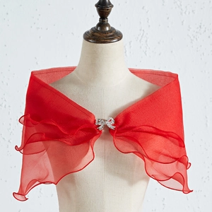 Detalle del chal de novia rojo con volantes en capas y broche de lazo con pedrería brillante