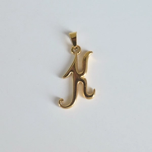 Détail macro du pendentif monogramme lettre K en acier inoxydable plaqué or 18K