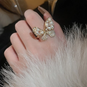 Close-up of gold-plated butterfly ring with artificial pearls and shimmering zircons