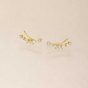 Detailed view of gold plated curved earrings featuring teardrop and round cubic zirconia