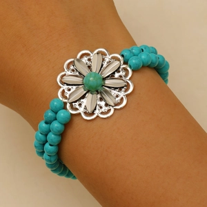 Bohemian turquoise bead bracelet set with vintage flower charm on a model's wrist
