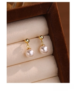 Detail of elegant S925 silver pearl stud earrings with gold metallic finish in a jewelry box